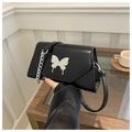 Detail of black faux leather crossbody bag with silver butterfly clasp and chain strap - Black