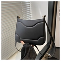 Detalle del bolso bandolera negro mate con relieve curvado texturizado y herrajes dorados en D - Negro