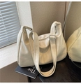 Borsa hobo beige patchwork con tracolla regolabile appoggiata a libri in luce soffusa - Bianco Sporco