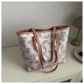 Detail view of butterfly print tote bag with pink leather handles and gold rivet accents - Pink