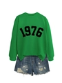 Nahaufnahme des grünen 1976-Sweatshirts kombiniert mit blauen Denim-Shorts im Used-Look - S / Grasgrünes Sweatshirt (Schwarze Schrift)