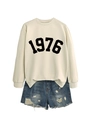 Detail of round neck sweatshirt with 1976 print and side slit hem paired with denim shorts - Sand Sweatshirt (Black Font)