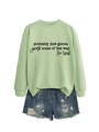 Detail of light green sweatshirt with black script text and distressed denim shorts - Olive Green Sweatshirt (Black Font)