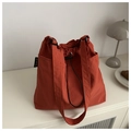 Caramel nylon drawstring tote bag on a white table with a lamp and croissant - Orange
