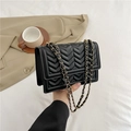 Klassische schwarze Stepptasche mit goldener Kette auf stilvollem Blazer - Schwarz