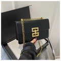 Close-up of black leather crossbody bag with elegant gold geometric metal buckle and chain - Black