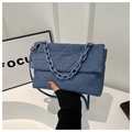 Close-up of blue denim shoulder bag featuring white quilted diamond patterns and chain - Dark Blue