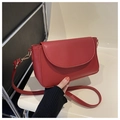 Close-up of red leather flap bag featuring elegant gold lobster clasp and D-ring hardware - Red