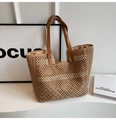 Detail der hohl gewebten Stroh-Tasche mit braunen Ledergriffen und gestreifter Textur - Khaki