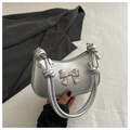 Detalle de un bolso hobo plateado con lazo decorativo y asa con un diseño de nudo exclusivo - Plateado
