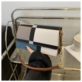 Détail d'un sac à bandoulière géométrique avec chaîne dorée et poignée en cuir élégante - Bleu Lac