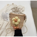 Detail of handwoven straw bucket bag with floral accent and faux pearl handle - Off White