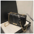 Detailaufnahme der schwarzen Stepptasche mit goldener Kette und edlem Metallbesatz - Schwarz