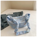 Dettaglio della borsa in tela ricamata azzurra con cuciture ondulate e tracolla annodata - Blu