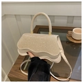 Elegante borsa beige con paillettes patta ondulata e manico tondo in un ambiente bar - Cachi