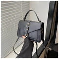 Close-up of a black textured leather crossbody bag featuring elegant gold clasp hardware - Black