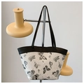 Detalle de un bolso tipo cubo francés con estampados de mariposas negras y asas en contraste - Negro