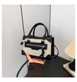 Detail van een minimalistische geweven handtas met zwarte lederen bies en rits - Zwart