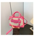 Detail van een felroze mini crossbody tas met geweven textuur en lange leren kwastjes - Rozerood