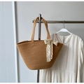 Gewebte Tasche in Camel mit weißer Spitzenschleife neben einem weißen Sommerkleid - Khaki