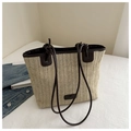 Detail der handgewebten Stroh-Tote-Bag mit braunen Lederriemen und Knotendetails auf Bett - Kaffee Groß