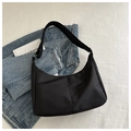 Close-up of minimalist black nylon crescent bag with adjustable wide strap on textured background - Black