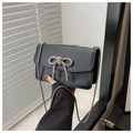 Detail view of black rectangular flap bag with rhinestone bow and silver chain strap - Black