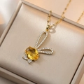Dettaglio macro di un ciondolo a coniglio dorato con gemma gialla e micro-diamanti brillanti - Collana Coniglio Giallo