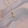 Elegant gold clover necklace set with sparkling white crystals on a purple silk fabric - Gold Pave Clover Necklace (X1226)