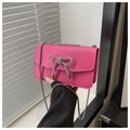 Détail d'un sac fuchsia avec un nœud en cristal et une bandoulière chaîne argentée - Rose rose
