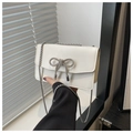 Detail of white square bag featuring a sparkling rhinestone bow and silver chain strap - White