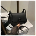 Detail view of the black lychee pattern leather saddle bag with round magnetic clasp - Black
