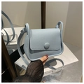 Detailed view of light blue saddle bag with pebble leather texture and round buckle - Blue