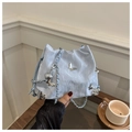 Detail der hellblauen Kordelzugtasche mit silbernen Schmetterlingen und Metallecken - Blau