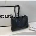 Close-up of black tote bag featuring white contrast stitching and a long shoulder handle - Black