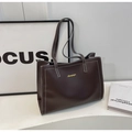 Close-up of large coffee PU leather tote bag with white contrast stitching and gold logo - Brown
