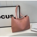 Detailed view of pink leather tote bag with gold logo on minimalist white surface - Pink