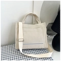 Primer plano del bolso tote de pana blanco crudo con correa ajustable sobre tela azul - Blanco Roto