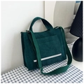 Detalle de bolso tote de pana verde oscuro con bolsillo lateral sobre mantel a cuadros - Verde