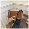 Detail view of a brown faux leather crossbody bag with a gold square twist lock clasp - Brown