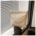 Close-up of beige woven texture and gold chain strap on a stylish bucket bag - White