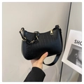 Détail de la texture crocodile noire sur un sac à bandoulière avec fermeture dorée - Noir