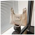 Detail der cremeweißen Ledertasche mit silberner Metallschleife und geknotetem Riemen - Weiß