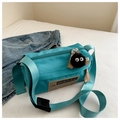 Close-up of turquoise oxford cylinder bag with XM label and black plush charm - With Pendant / Blue