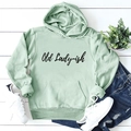 Flat lay of a mint green hoodie with Old Lady-ish text, jeans, and white sneakers - Light Green (Black Text)