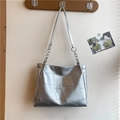 Borsa tote argento con cuciture geometriche e catene appesa a un gancio di legno - Argento