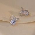 Elegant silver bow earrings with zircon stones on champagne silk fabric background - Silver