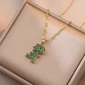 Titanium dinosaur pendant necklace with emerald green zircons on gold chain display - Gold Dinosaur Necklace