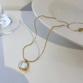 Titanium steel necklace with 18K gold square shell pendant on a white plate - White Mother of Pearl Square (T0158)