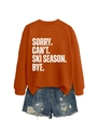 Detail of orange crewneck sweatshirt with Sorry Can't Ski Season Bye text and denim shorts - Burnt Orange (White Font)